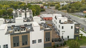 A multi-story building with a rooftop terrace featuring outdoor seating and air conditioning units.