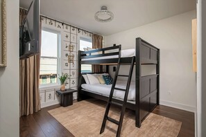 A bunk bed room with a TV, a small table, a plant, and a window with curtains. - Hot tub Nashville home for families • 3BR sleeps 10 near Broadway (Nashville)