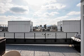 A rooftop terrace with a grill, a view of the city skyline, and a railing. - Hot tub Nashville home for families • 3BR sleeps 10 near Broadway (Nashville)