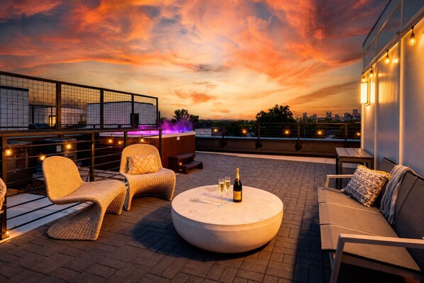 A rooftop terrace with wicker furniture, a round table with a bottle and glasses, and string lights. - Fall getaway: hot tub house sleeps 10 near Germantown, Nashville (Nashville)