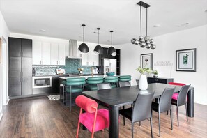 A modern kitchen with dark cabinets, a central island with stools, and pendant lighting.
