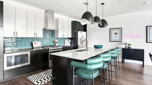 A modern kitchen with a central island, bar stools, stainless steel appliances, and pendant lighting. - Nashville hot tub Skyline Deck home, sleeps 10, 3BR near Germantown (Nashville)