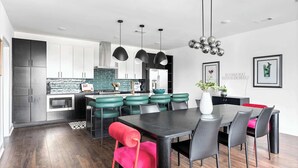 A modern kitchen with dark cabinets, a central island with stools, and pendant lighting. - Nashville hot tub house sleeps 10, 3 bedrooms near Broadway (Nashville)