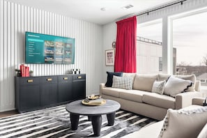 A modern living room with a flat-screen TV, a dark-colored cabinet, a beige sofa, and a round coffee table.