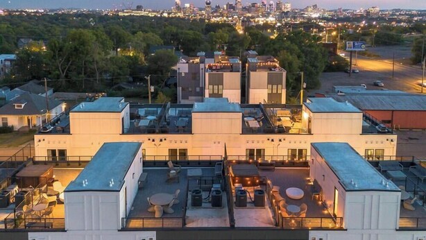 A modern building with a rooftop patio area featuring outdoor seating and a view of the city skyline. - Nashville hot tub house sleeps 10, 3 bedrooms near Broadway (Nashville)