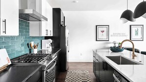 A modern kitchen with a black stove, stainless steel appliances, and a white countertop. - Nashville hot tub house sleeps 10, 3 bedrooms near Broadway (Nashville)