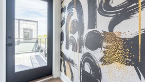 Et moderne værelse med et stort vindue, en dør og en væg med abstrakt kunst.