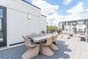 An outdoor patio with a table and chairs, a white building, and a view of other buildings in the background. - Fall getaway: bold design home sleeps 12, chef kitchen, 4BR/3.5BA in Nashville (Nashville)