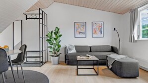 Un moderno apartamento tipo loft con comedor, un sofá gris, una mesa de centro y un amplio ventanal con cortinas.