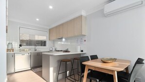 Una cocina moderna con armarios blancos, una isla central y un comedor con mesa de madera y sillas negras.