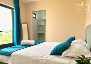 Une chambre d’hôtel avec un lit, une grande fenêtre avec des rideaux, une armoire et un miroir.
