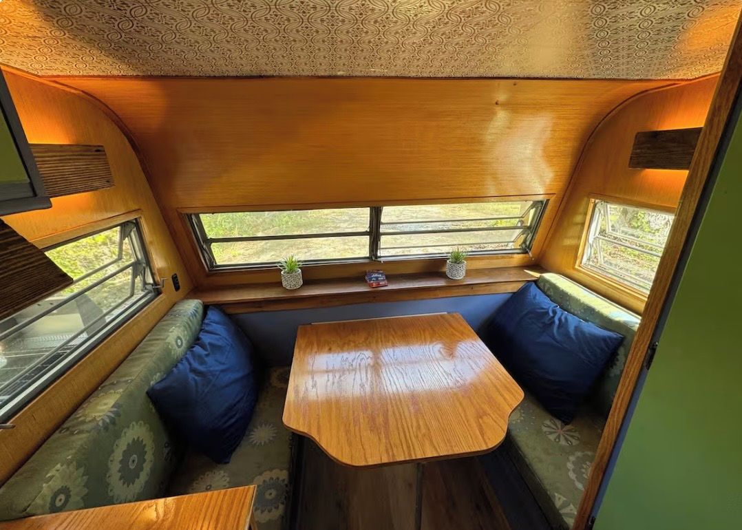 Ein gemütliches Interieur mit Holztisch und Bank, einem Fenster mit Ausblick und einer gemusterten Decke.