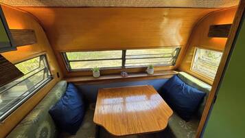 Ein gemütliches Interieur mit Holztisch und Bank, einem Fenster mit Ausblick und einer gemusterten Decke.