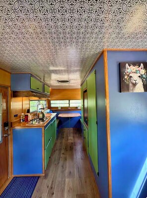 A compact kitchen with a central island, wooden cabinets, and a patterned ceiling.