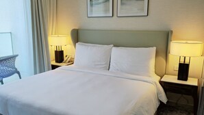 Hotelkamer met een groot bed, twee nachtkastjes met lampen, een stoel en twee wanddecoraties.