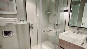 Een moderne badkamer met een douchecabine van glas, een wit toilet en een wastafel met spiegel.