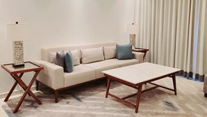 Een moderne woonkamer met een beige bank, een houten salontafel en een kamerkleed met een patroon.