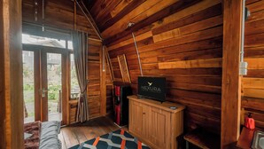 Een knus houten huisje met een bed, een televisie en een kleine badkamer.