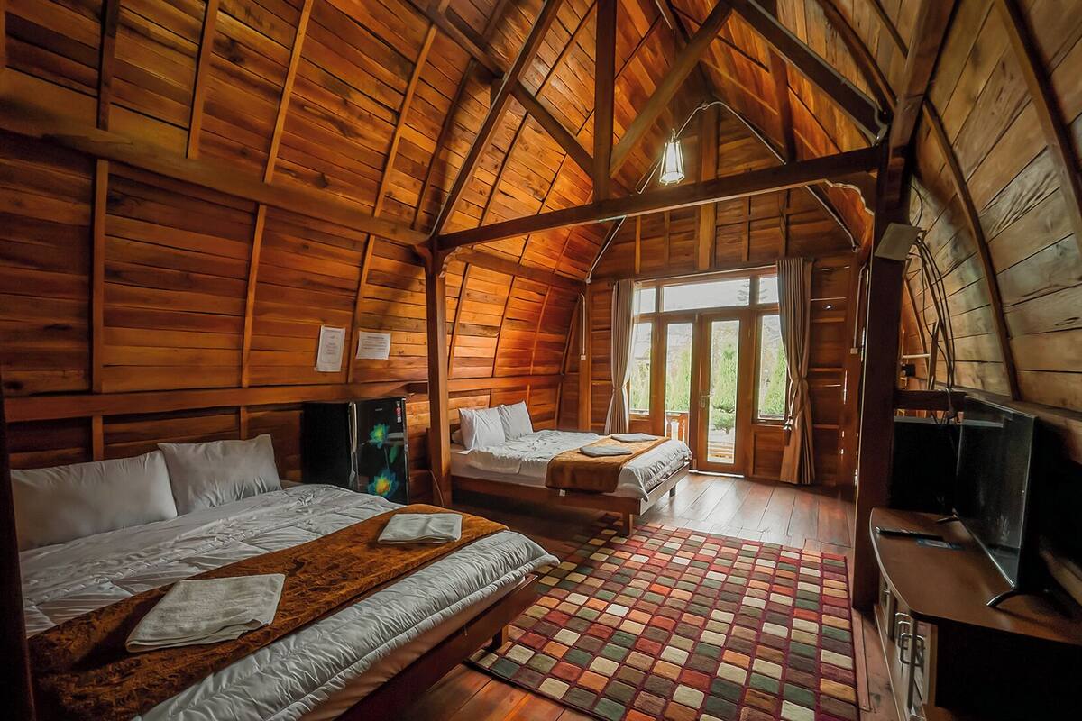 Una cabaña de madera con dos camas, un televisor y un refrigerador.
