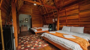 Una cabaña acogedora de madera con dos camas, suelo de madera y una pequeña cocina americana.
