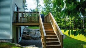 Eine Holzterrasse mit einer Treppe, die zu einem Balkon im zweiten Stock führt.