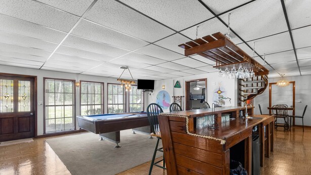A spacious room with a pool table, wooden bar, and a staircase. - Parrothead Retreat - Steinhatchee (Steinhatchee)