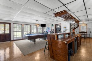 A spacious room with a pool table, a bar area, and a dining space.