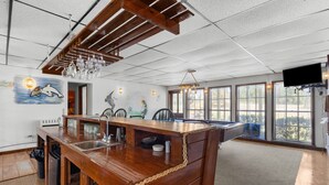 A spacious kitchen with a wooden bar, large windows, and a mural of a dolphin. - Parrothead Retreat - Steinhatchee (Steinhatchee)