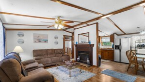 A spacious living room with a brown sofa, a glass coffee table, and a fireplace. - Parrothead Retreat - Steinhatchee (Steinhatchee)
