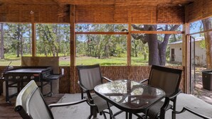 An outdoor patio with a glass table and chairs, a grill, and a view of a wooded area. - Parrothead Retreat - Steinhatchee (Steinhatchee)