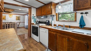 A compact kitchen with wooden cabinets, a stove, a dishwasher, and a sink. - Parrothead Retreat - Steinhatchee (Steinhatchee)