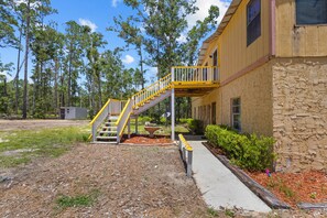 A building with a stone facade and a wooden deck with yellow railings. - Parrothead Retreat - Steinhatchee (Steinhatchee)