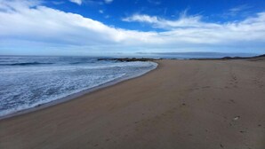 A wide sandy beach with gentle waves and a clear sky. - SeaHen Lodge - entire house - rustic farmhouse charm with amazing mountain views (Zeehan)