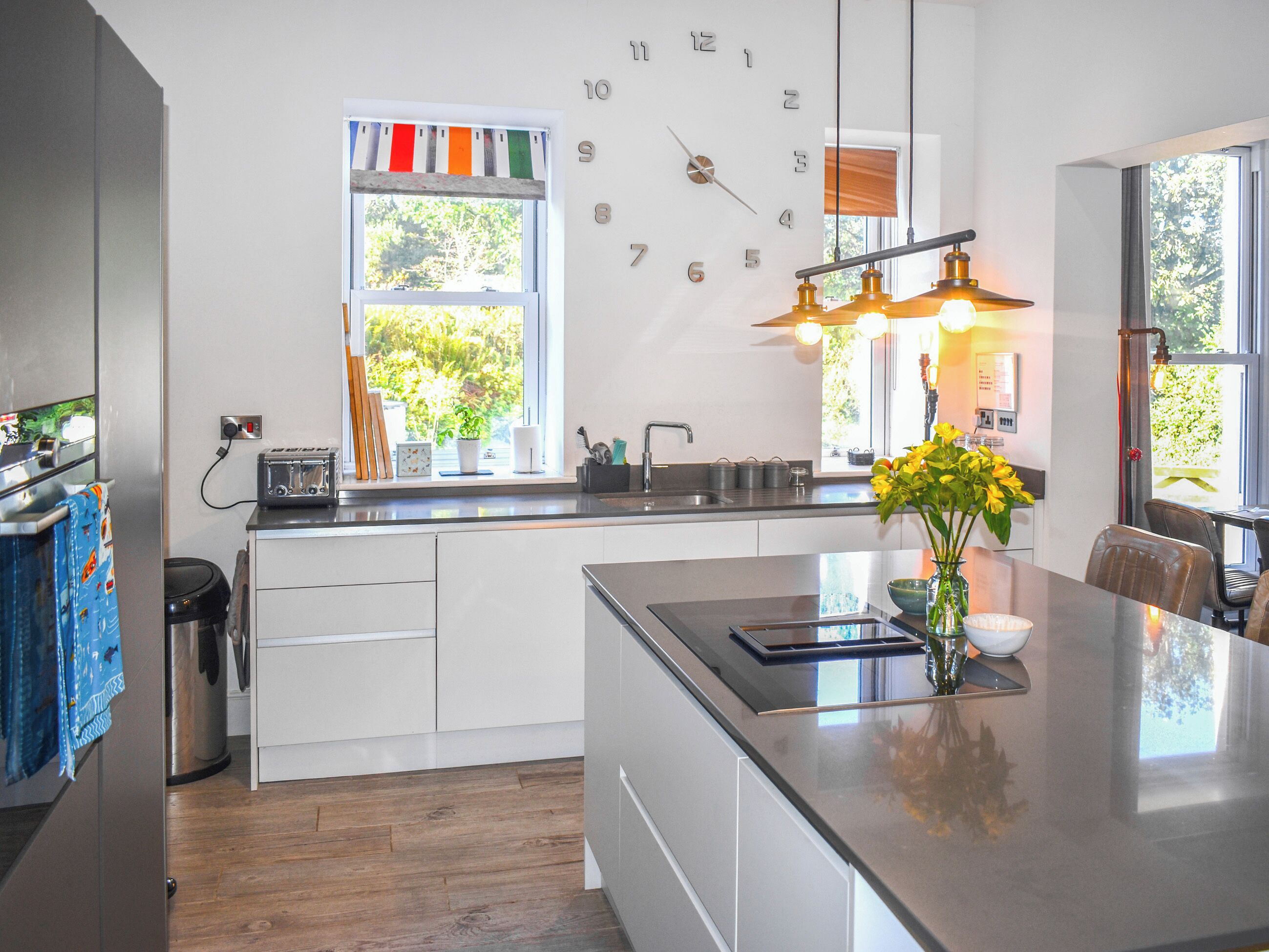 A modern kitchen with a central island, a built-in oven, and a window with a view of greenery.
