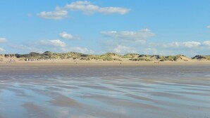 Uma praia com dunas de areia e céu claro.
