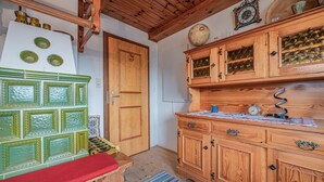 A wooden kitchen with a bench, a clock, and a patterned rug. - Quaint holiday home with garden and views (Oberndorf in Tirol)