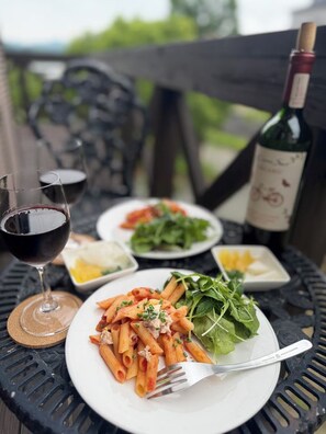 Ein Tisch mit Pasta, einem Weinglas und einer Weinflasche im Freien.