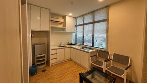 Eine kompakte Küche mit Fenster, ein Essbereich mit Glastisch und eine eingebaute Sitzbank.