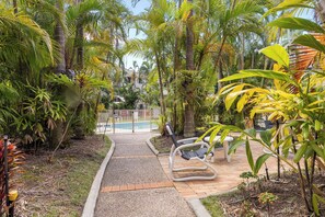 Un sentiero conduce a un'area piscina circondata da vegetazione tropicale.