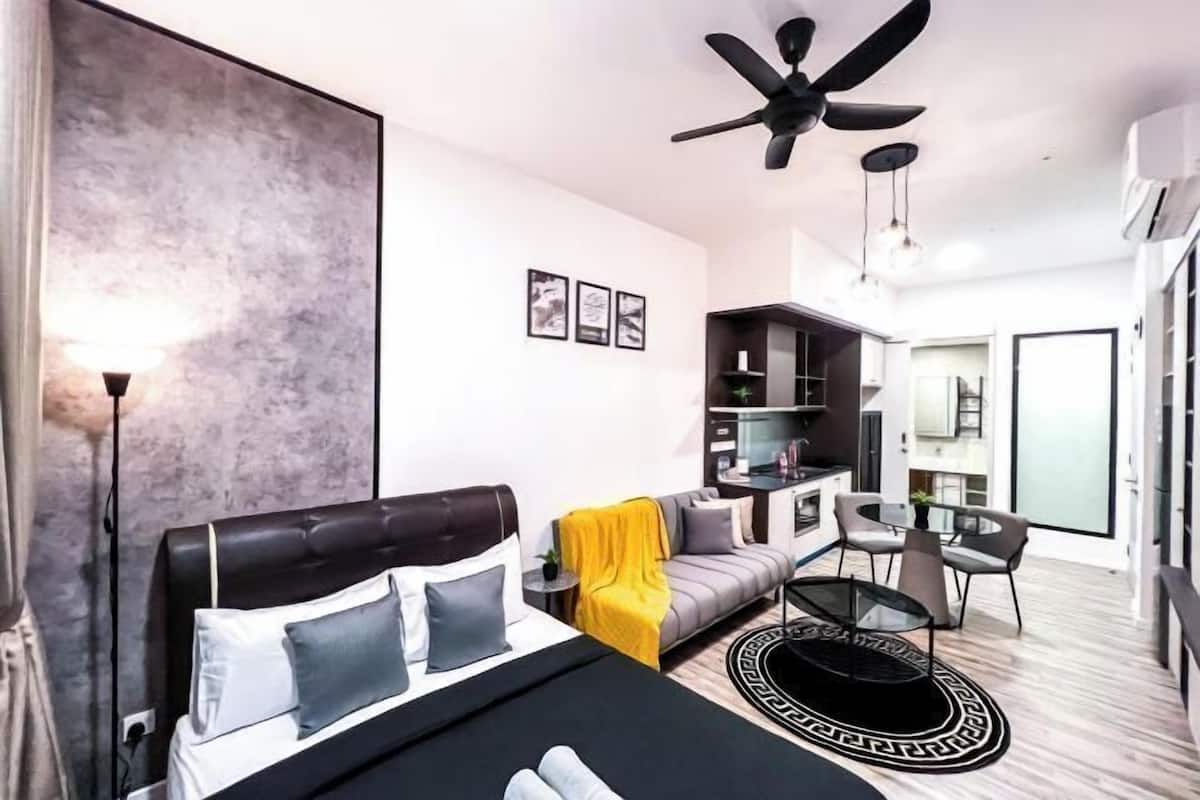 Una habitación de hotel moderna con una cama, un sofá, un comedor y un ventilador de techo.