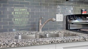Una cucina con piano di lavoro in granito, lavello in acciaio inossidabile e piano cottura nero.
