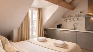 A modern bedroom with a large bed, a kitchenette, and a sloped ceiling. - Place des Vosges - Deluxe apartment for 4 (Paris)