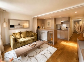 A modern living room with a sofa, a coffee table, and a kitchen area with a bar and counter.