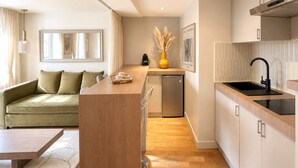 Una cocina moderna con isla integrada, una zona de comedor con sofá y un refrigerador compacto.