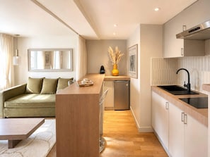 A modern kitchen with a built-in island, a dining area with a sofa, and a compact refrigerator.
