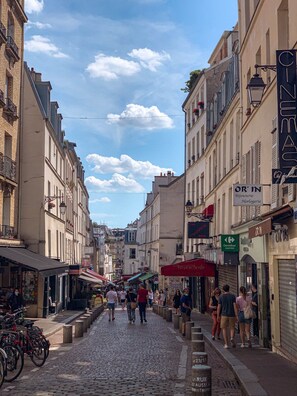 A cobblestone street lined with buildings, some with signage indicating shops and services.