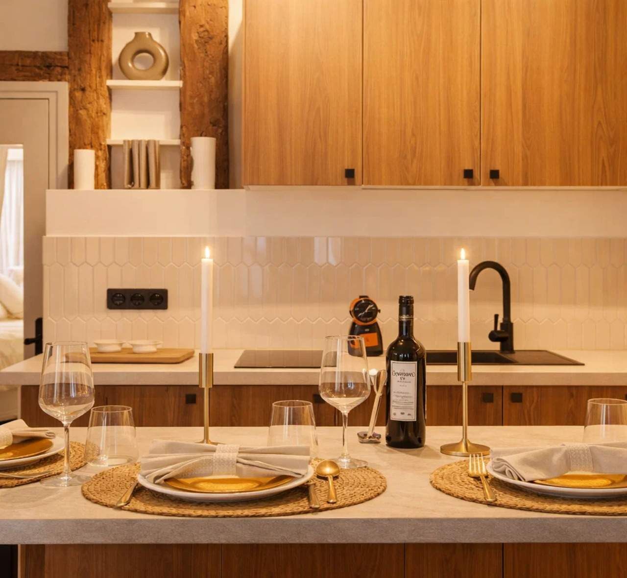 Een moderne keuken met houten kastjes, een wit aanrecht en een eethoek met borden, glazen en een fles wijn.