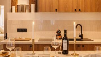 Een moderne keuken met houten kastjes, een wit aanrecht en een eethoek met borden, glazen en een fles wijn.
