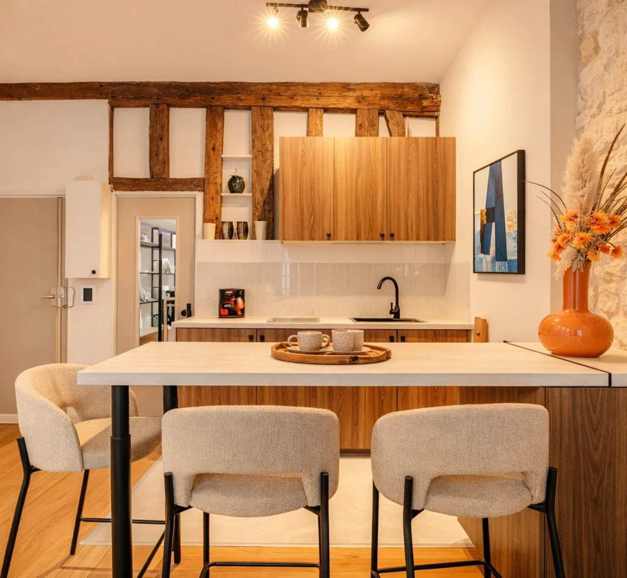 A modern kitchen with wooden cabinets, a central island with bar stools, and a decorative vase.