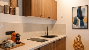 A modern kitchen with wooden cabinets, a countertop, a coffee machine, and a sink. - Marais stylish & central studio (Paris)